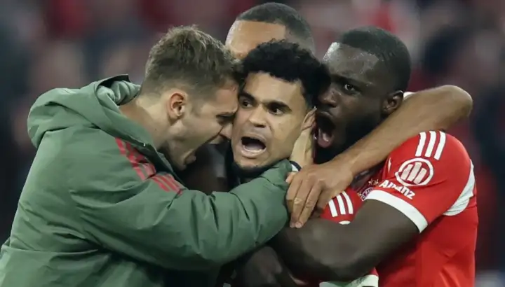 Luis Díaz festeja con júbilo su gol decisivo ante el Real Madrid en los cuartos de final de la Champions League, acompañado por jugadores del Bayern Múnich frente a la afición bávara.