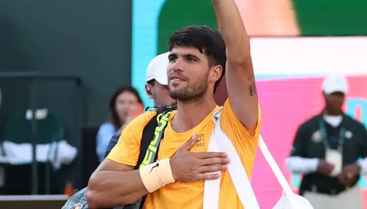 "Carlos Alcaraz agradece al público con la mano en el pecho tras un partido; una imagen cargada de simbolismo ahora que su presencia en Roland Garros está en duda por lesión."